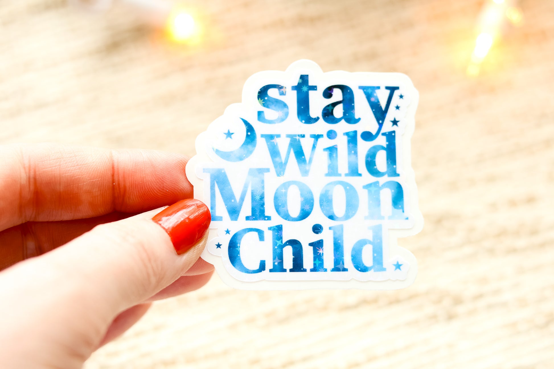 a hand holding a sticker that says stay weird moon child