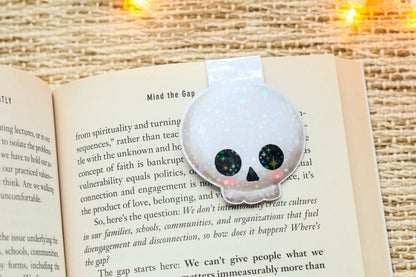 an open book with a skull brooch sitting on top of it