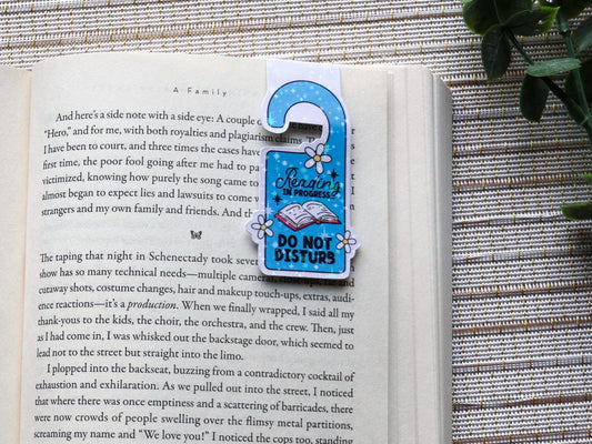 Blue and white magnetic bookmark in the shape of a door hanger that reads &quot;Reading in progress... do not disturb&quot;